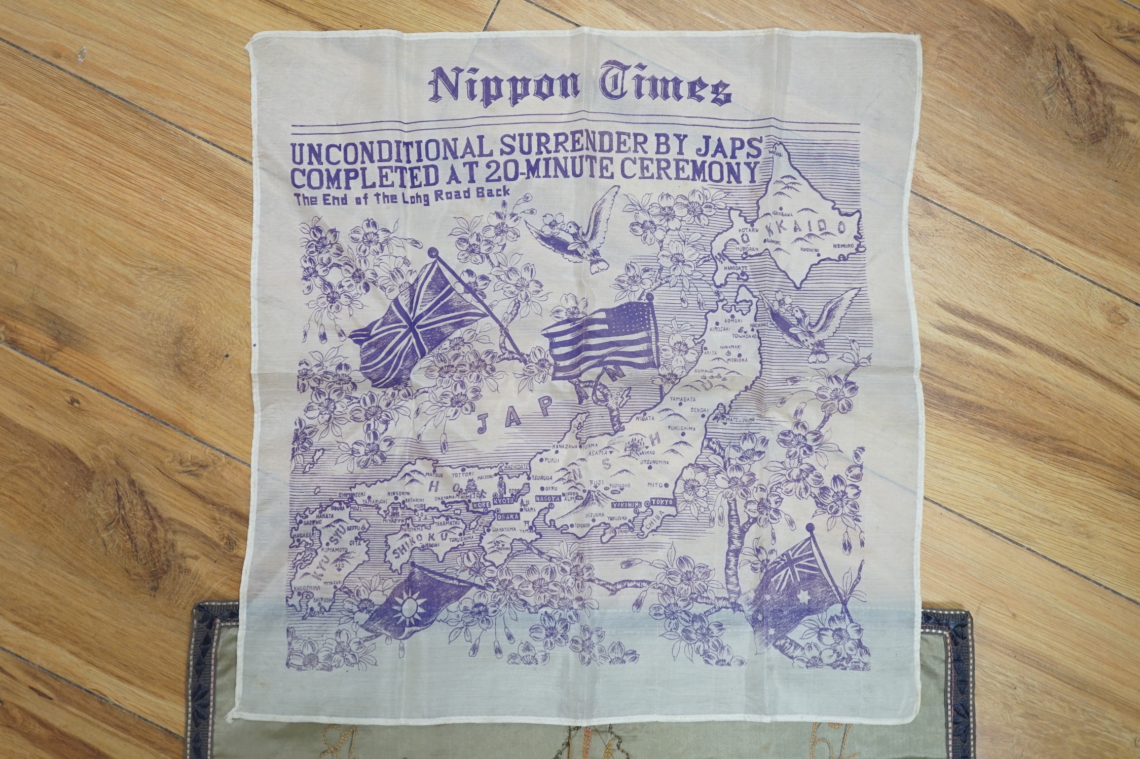 A WWII silk printed handkerchief; ‘Nippon Times’ commemorating the surrender of the Japanese, together with a WWI Army Service Corps emblem dated 1918, 44 x 45cm